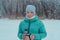 15-year-old girl walking in  winter forest holds thermos and mug of hot tea. Picnic in the snow