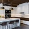 16 A sleek, modern kitchen with a mix of white and stainless steel finishes, a large island with seating, and a mix of open and