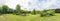 This is a 180 degree panoramic photo of a beautifully landscaped garden with a great diversity of trees and flowering shrubs near