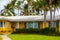 1950`s Florida home painted yellow with green grass and palm tre