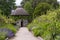 The 19th Century thatched round house surrounded by beautiful flower beds and gravel paths in the walled garden at West Dean garde