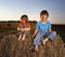 2 boys in a haystack in the field in summer