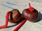 2 brown conkers sitting on a table threaded with strings ready to play