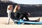 2 Caucasian surfers sitting on the beach watching the sea