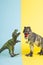 2 dinosaurs fighting on a yellow and blue background