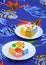 2 dishes of various mini cakes on colorful tablecloth in vertical frame