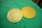 2 explanted cleaned silicone breast implants lie on a green surgical drape