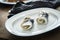 2 German Rollmops rolled pickled herring with gherkin onion filling on porcelain plate with cutlery, kitchen towel and dark wooden