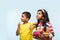 2 indian kids flying kite, one holding spindal or chakri