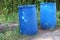2 large blue plastic bins set on the ground outdoor litter concept
