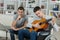 2 male teenagers playing acoustic guitar and singing