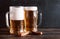 2 mugs of beer with foam and snacks, croutons on a dark wooden background