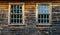 2 multiple paned windows in a weathered and charred wooden wall