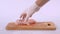 2 pieces of raw chicken fillet falls on a wooden board, than taken from a wooden plank by hand