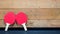 2 ping pong paddles against a wooden wall