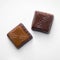 2 square candies made of milk and dark chocolate on a white background