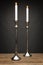 2 tall silver candle holders and glowing candles, shot on a wooden table