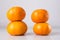 2 turrets of 4 ripe tangerines on a light gray background