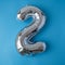 2 two metallic balloon isolated on blue background. Greeting card silver foil balloon number Happy birthday holiday