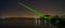 2 visible beams of laser light, red and green, focusing in the direction of Lisbon, crossing the Tagus River