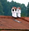 2 white chimneys plastered with brick cover on a tiled roof  3