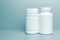 2 white jars for medicines and vitamins and dietary supplements without a name are on a gray shelf