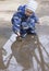 A 2 -year-old boy playing with a leaf in a puddle