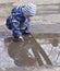 A 2 -year-old boy playing with in a puddle