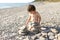 2 years toddler building pebbles tower on the beach