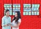 2 young women with tablet looking the new office lines. Red wall of bricks with windows