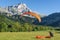 2018-08-26 Mens, France. Paraglider pilots land on a grass meadow with high rocky mountain peak on the background