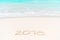 2018 handwritten on sandy beach with soft ocean wave on background