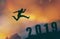 2019 brave man successful concept,silhouette man jumping over the sun between gap of the mountain to 2019 new year, feel like a wi