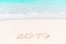 2019 handwritten on sandy beach with soft ocean wave on background