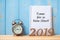 2019 Happy New years with Time for a New Start text on notebook, retro alarm clock and wooden number on table and copy space.