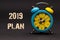 2019 plan written with alarm clock on black paper background