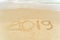 2019 written on sandy beach with wave approaching