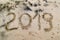 2019 written on the sea sand with foot prints.