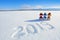 2019 written on the snow. Smiling snowman with hats and scarfs are standing on the field with snow. Landscape with mountains.