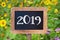 2019 written on a wooden sign, Sunflowers and wild flowers