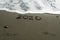 2020 and footprints on beach sand