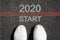 2020 Start. The inscription on the pavement. Two white sneakers. Top View. The concept of the beginning of the new year.
