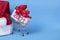 2021 text on gift box with red ribborn, santa claus hat and shopping trolley. Blue background. Christmas and New Year purchase