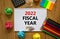 2022 fiscal new year symbol. White note, words 2022 fiscal year on beautiful wooden table, colored paper, colored pencils, paper