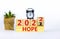 2022 hope new year symbol. Alarm clock. Turned a wooden cube, changed words `Hope 2021` to `Hope 2022`. Beautiful white backgr