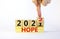 2022 hope new year symbol. Businessman turns a wooden cube and changes words `Hope 2021` to `Hope 2022`. Beautiful white