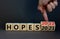 2022 hopes new year symbol. Businessman turns wooden cubes and changes words `Hopes 2021` to `Hopes 2022`. Beautiful grey