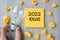 2022 Idea words on yellow note and crumbled paper with Businessman holding lightbulb on wooden table background. New Year New