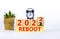 2022 reboot new year symbol. Alarm clock. Turned a wooden cube, changed words `Reboot 2021` to `Reboot 2022`. Beautiful white