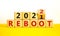 2022 reboot new year symbol. Turned a wooden cube and changed words `Reboot 2021` to `Reboot 2022`. Beautiful white background
